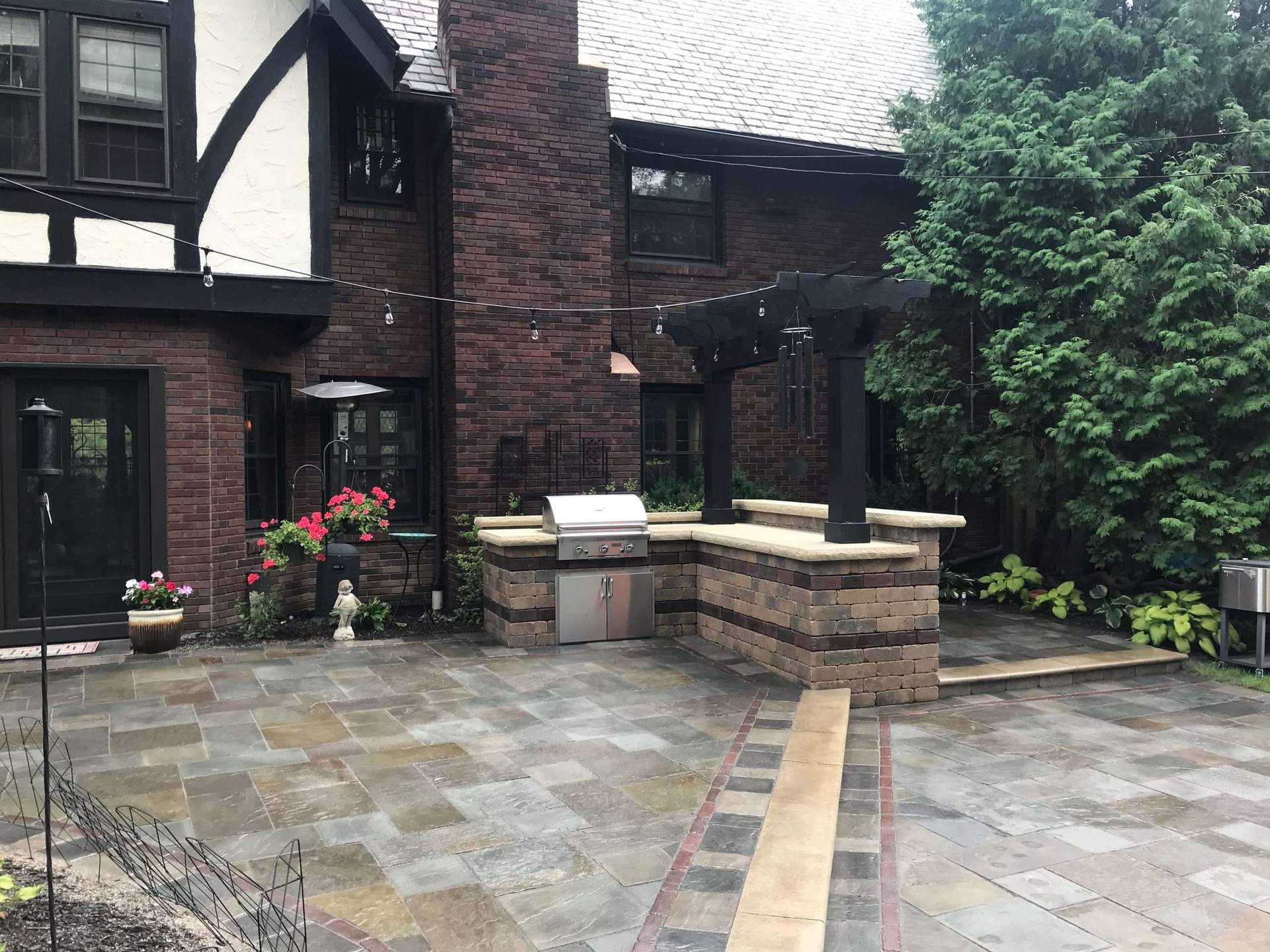 Outdoor kitchen and paver patio with brick home backdrop